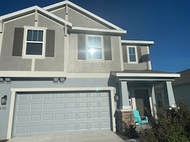 A two-story house with a garage, a covered porch, and a small front yard.