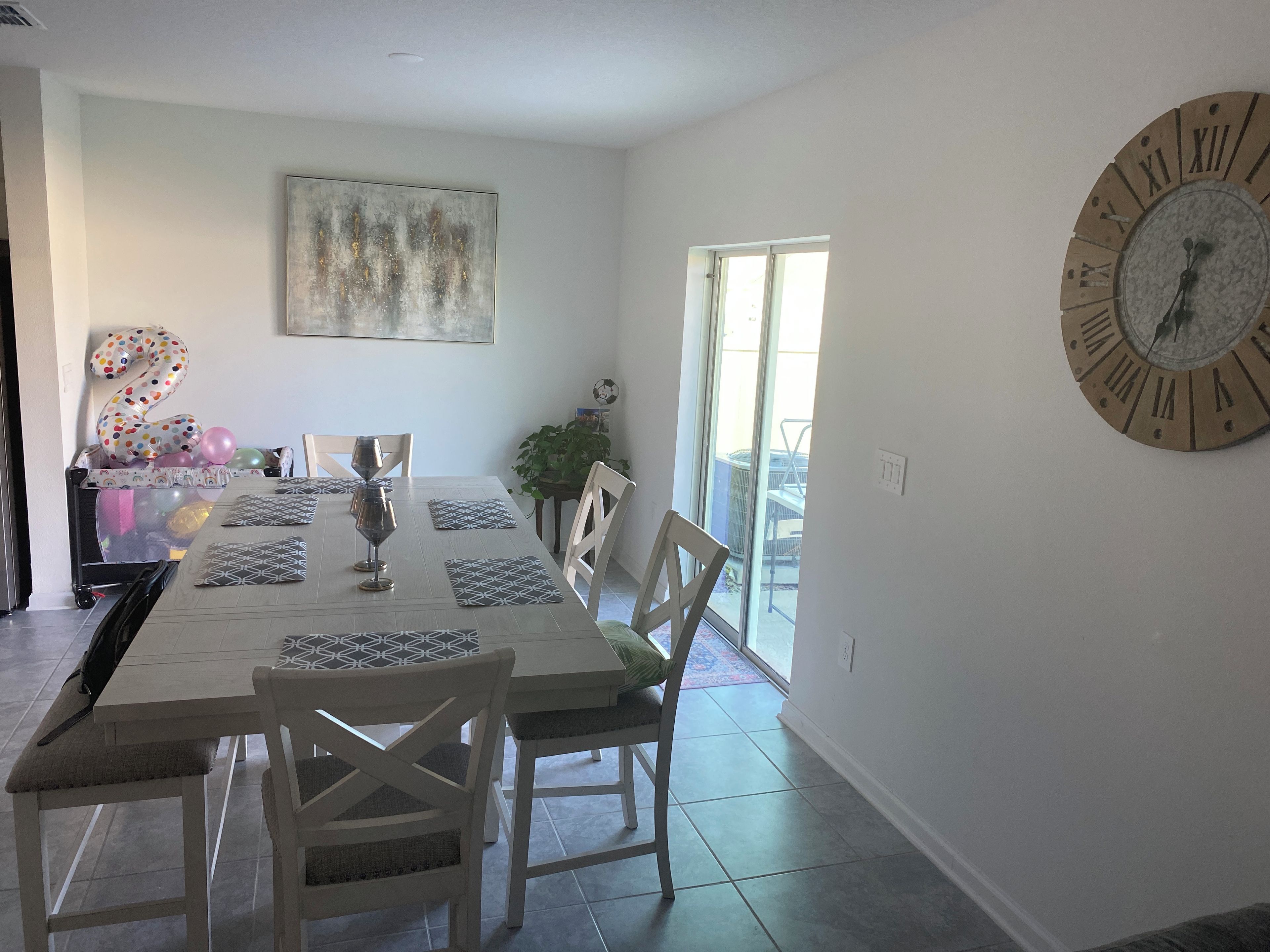 A dining area with a large table, chairs, and a wall clock.