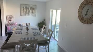 A dining area with a large table, chairs, and a wall clock.