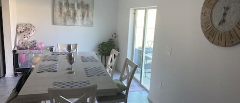 A dining area with a large table, chairs, and a wall clock.