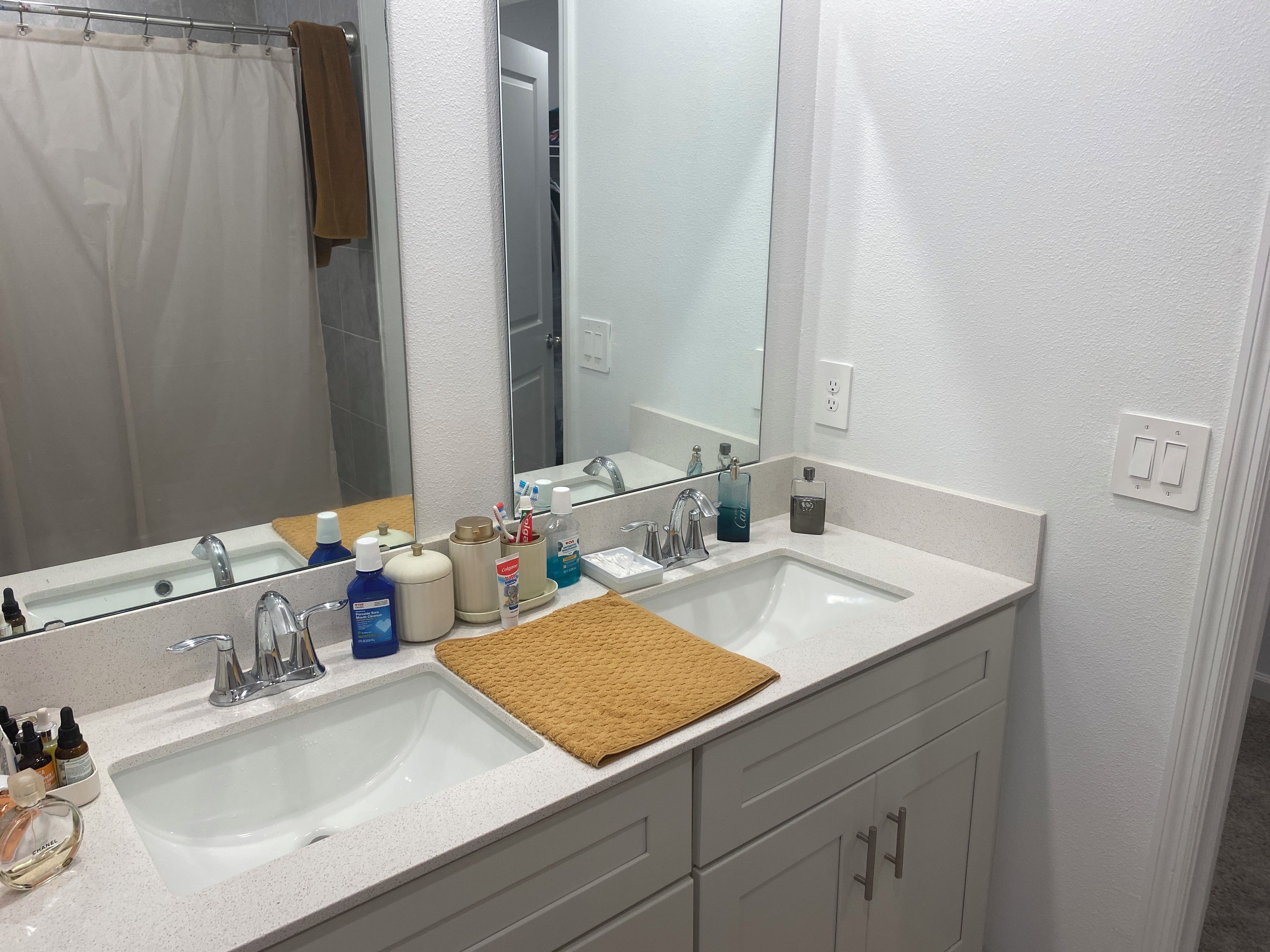 A bathroom with two sinks, a large mirror, and a towel rack.