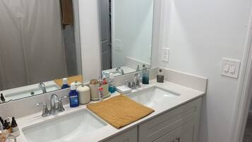 A bathroom with two sinks, a large mirror, and a towel rack.
