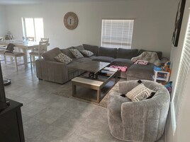 Uma sala de estar moderna com sofá seccional, mesa de centro e área de jantar com cadeiras e mesa.
