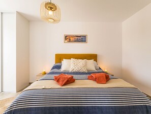 A hotel room with a bed, a nightstand, a lamp, and a painting on the wall. - Central apartment with parking - 4 guests (Saint-Michel-Chef-Chef)
