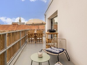 A balcony with a table, chairs, a hanging chair, and a small table with a decorative item. - Central apartment with parking - 4 guests (Saint-Michel-Chef-Chef)