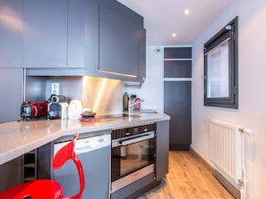 A modern kitchen with built-in appliances, a window, and a radiator. - Apartment with Wood Stove and Direct Slope Access (Val-d'Isère)
