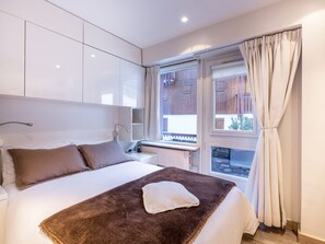 A bedroom with a bed, a bedside table, a window with curtains, and a view of the outside. - Apartment with Wood Stove and Direct Slope Access (Val-d'Isère)
