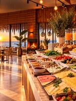 Un bufé con diversos alimentos, una chimenea y vistas al océano.