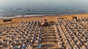 A beach with numerous sun loungers and umbrellas arranged in rows. - Goga otel (Türkiye)