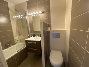 Ein modernes Badezimmer mit einer Badewanne, einem Waschbecken, einer Toilette und einer Duschkabine.