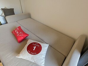 Ein Sofa mit einem roten Kissen und einem weißen Kissen mit rotem Kreis und Text.