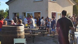 An outdoor gathering with people around tables and a building in the background.