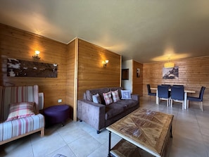 Ein gemütliches Zimmer mit einer Couch, einem kleinen runden Tisch und einer Essecke mit Stühlen.