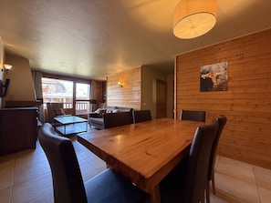 Un comedor con mesa y sillas de madera, un sofá y una lámpara fijada a la pared.