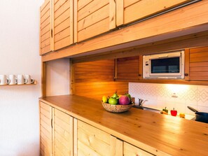 A kitchen with wooden cabinets, a microwave, and a fruit bowl on the counter. - Comfortable apartment with parking - 6 guests (Val-d'Isère)