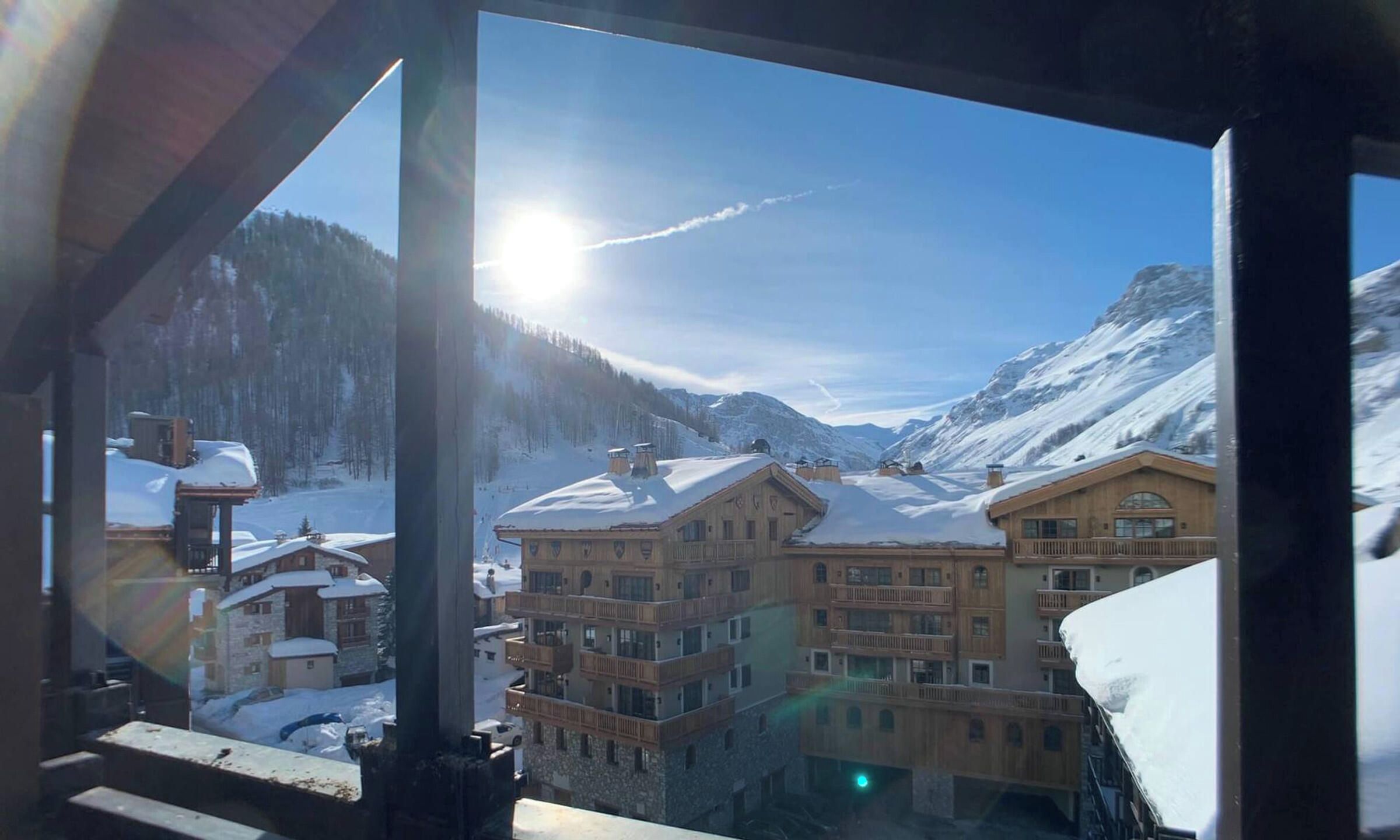 Ein Bergdorf mit mehreren Gebäuden, schneebedeckten Dächern und blauem Himmel.