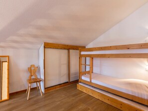Una camera con un letto a castello, una sedia di legno e una porta scorrevole.