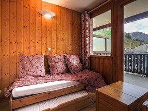 Ein gemütlicher Holzraum mit einem Bett, einem Tisch und einem Fenster mit Blick auf eine reizvolle Landschaft.