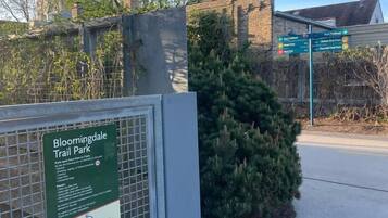 Un panneau indiquant l’entrée du parc Bloomingdale Trail, avec une clôture en métal et un buisson.