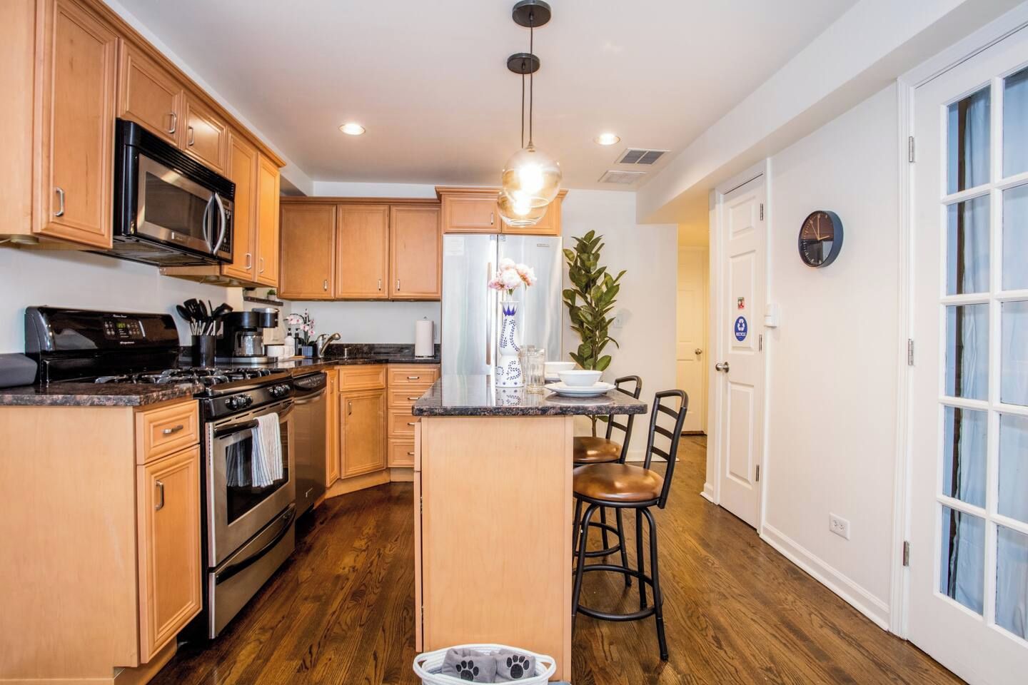 A modern kitchen with wooden cabinets, stainless steel appliances, and a central island with bar stools.