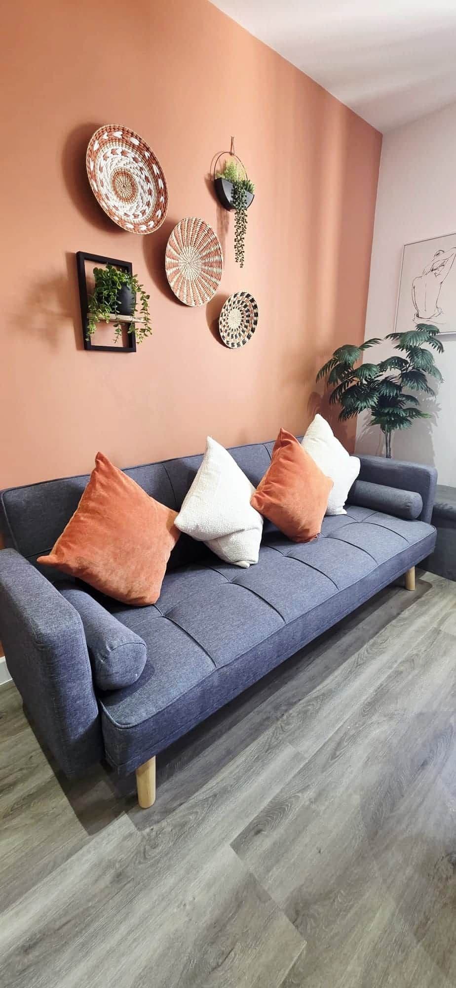 A modern living room with a grey sofa, multiple cushions, and decorative wall art.