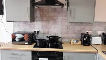 A modern kitchen with grey cabinets, a black stove, and a tiled backsplash.