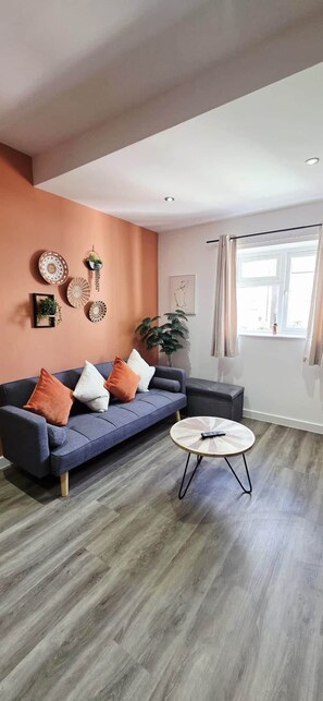 En stue med en sofa, et rundt sofabord og en potteplante.