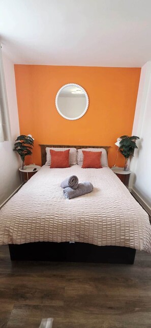 Ein Hotelzimmer mit einem Bett, einem runden Spiegel an der Wand und zwei Nachttischen mit Pflanzen.