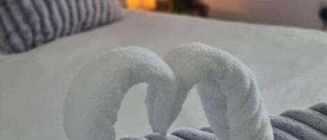 Una cama con una manta y dos toallas dispuestas en forma de cisne.