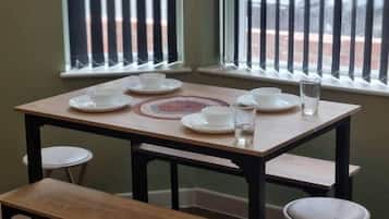 Una mesa de comedor con cuatro sillas, un banco y una ventana con persianas verticales.