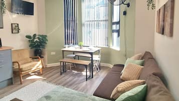 Una sala de estar con un sofá, una mesa de comedor y un televisor.