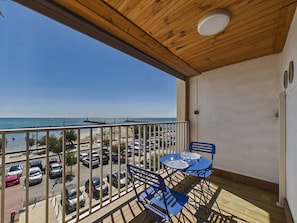 Ein Balkon mit Blick auf den Strand und geparkte Autos.