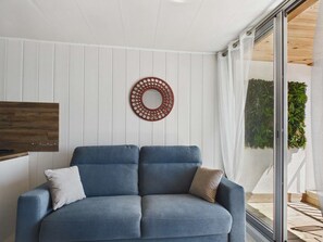 Una sala de estar moderna con un sofá azul, un estante de madera fijado a la pared y un adorno circular en la pared.