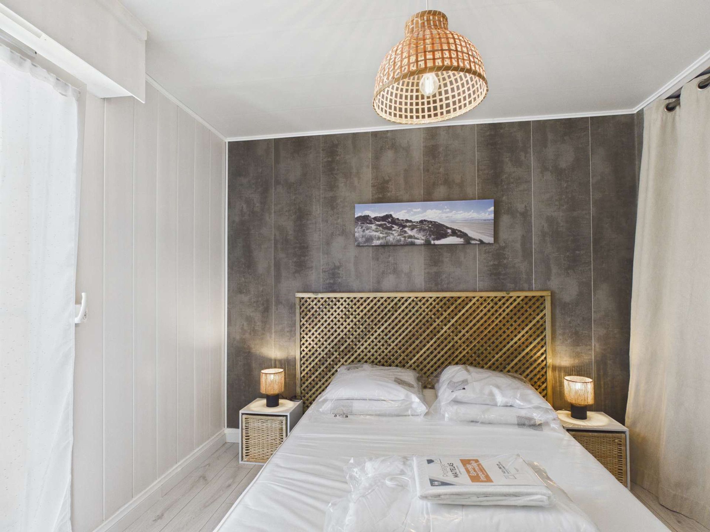 Ein Hotelzimmer mit Bett, zwei Nachttischlampen, einem Wandbild und einer Deckenleuchte.