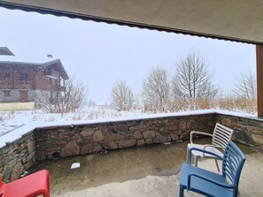 A stone wall patio with a view of a snow-covered landscape and buildings. - Les Menuires - 3 rooms, 6 pers, terrace, pool access (Les Menuires)