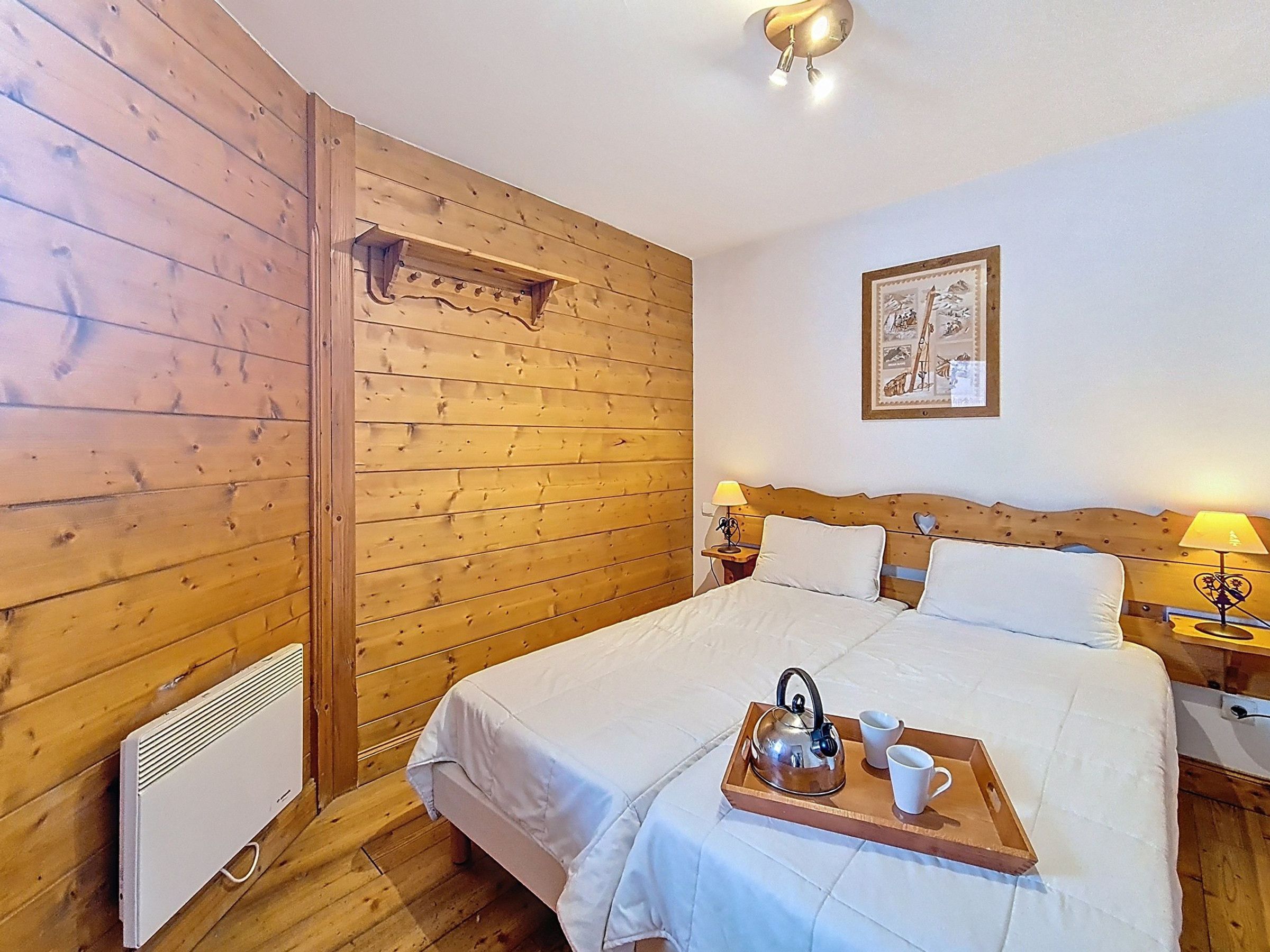 Una habitación con paneles de madera, una cama, un radiador y un cuadro en la pared.