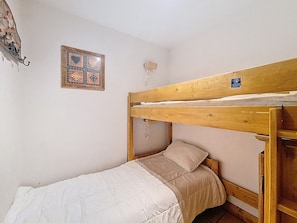 A single-occupancy room with a bunk bed, a small wall-mounted shelf, and a framed picture. - Les Menuires - 3 rooms, 6 pers, terrace, pool access (Les Menuires)
