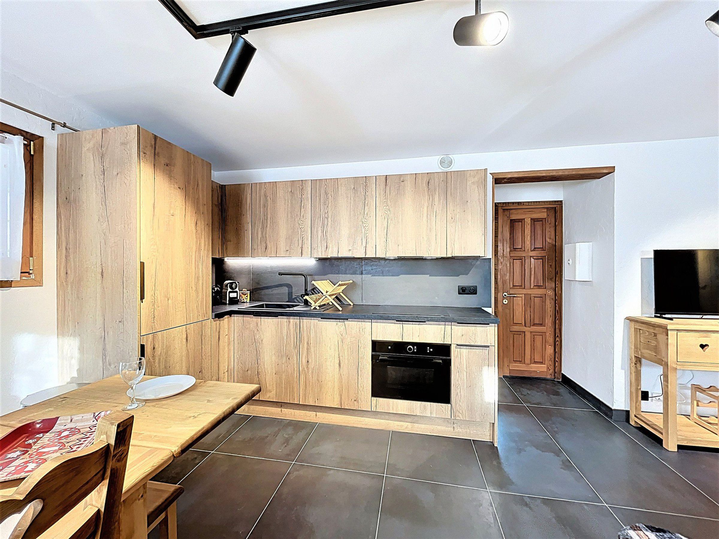 Une cuisine moderne avec des meubles en bois, un plan de travail noir et un four encastré.