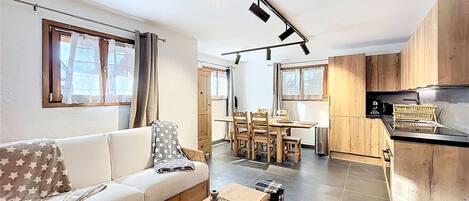 A modern living room with a sofa, a wooden coffee table, and a dining area with chairs and a table.