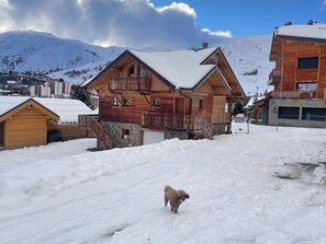 Eine Holzchalet mit Balkon, umgeben von schneebedeckten Bergen.