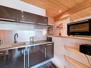 A modern kitchen with stainless steel appliances, a microwave, and a wooden ceiling. - Spacious apartment, 3 rooms, pets allowed, parking, Les Menuires (Les Menuires)