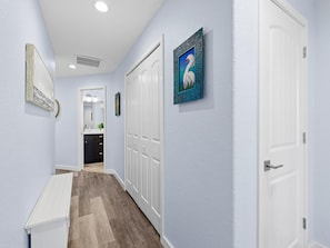 Un pasillo con un banco blanco, una puerta con cerradura y un cuadro en la pared.
