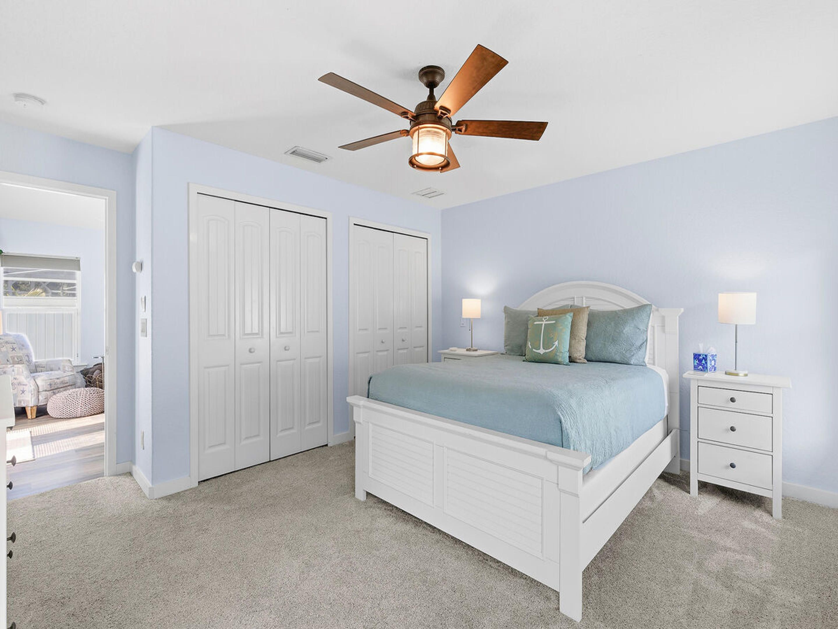 A bedroom with a bed, nightstands, a ceiling fan, and a closet.