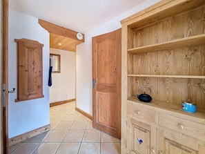 A hallway with wooden doors, a tiled floor, and a wooden cabinet with a kettle and a can. - Spacious 3-room apartment near slopes with terrace, pool and parking (Les Menuires)