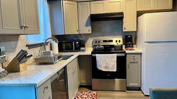 A kitchen with light-colored cabinets, a stainless steel stove, a microwave, and a refrigerator.
