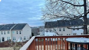 A deck with a table and chairs, overlooking a residential area with houses. - Cozy Home Away From Home (Woodbridge)