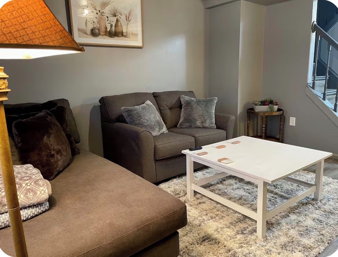 A living room with a sofa, a coffee table, a lamp, and a framed picture on the wall.