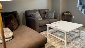 A living room with a sofa, a coffee table, a lamp, and a framed picture on the wall. - Cozy Home Away From Home (Woodbridge)
