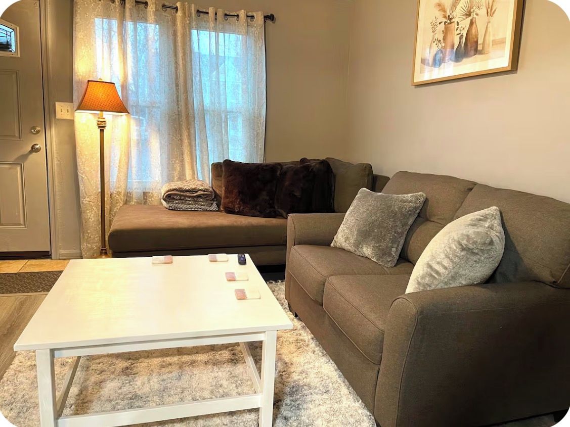 A living room with a sofa, a white coffee table, a lamp, and a door.