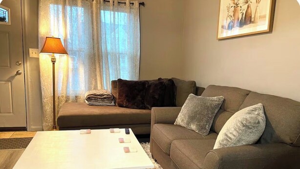 A living room with a sofa, a white coffee table, a lamp, and a door. - Cozy Home Away From Home (Woodbridge)
